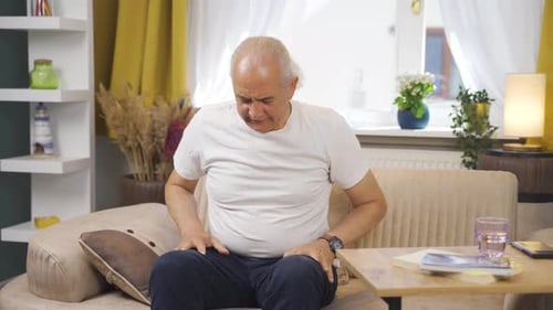 Senior Man Massaging Sore Shoulder in Living Room