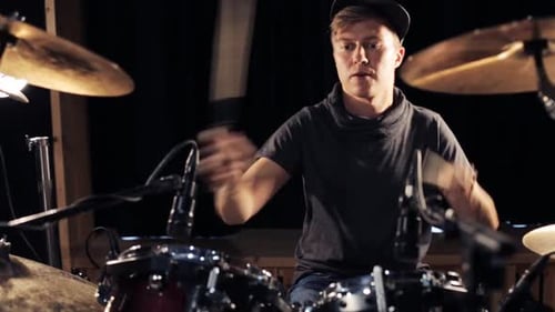 Male musician playing drums and cymbals at a live rock concert performance