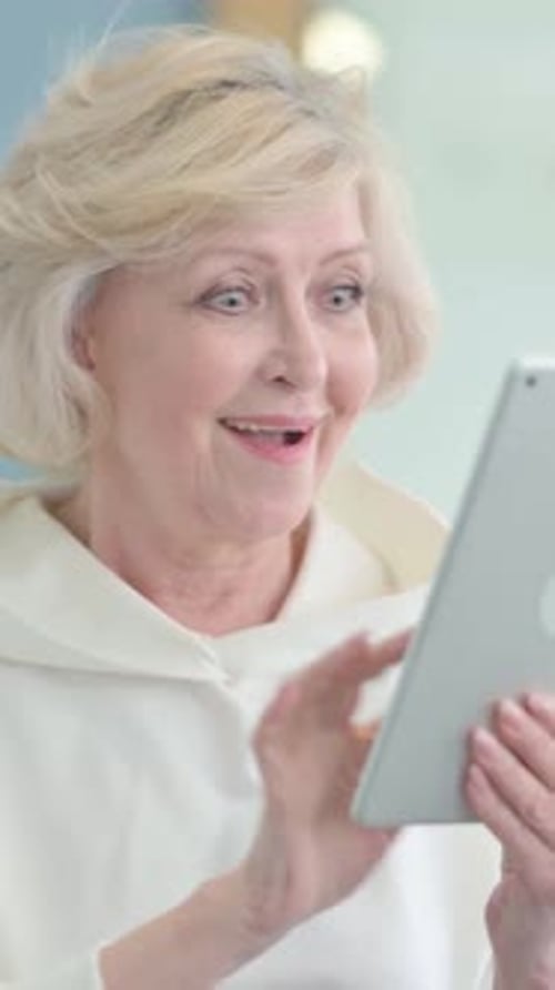 Senior Woman Interacts with Tablet Device at Home