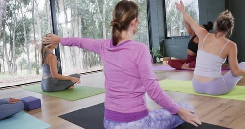 Women Doing Yoga Arm Extension Exercise in Studio