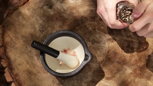 Adding Pepper to Salt in Mortar on Wood