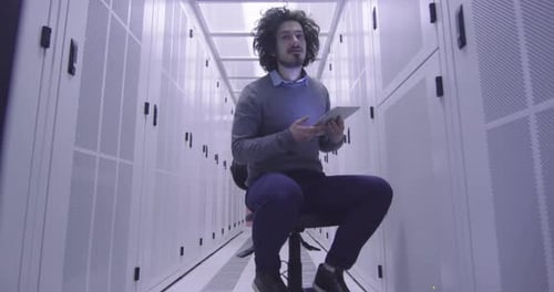 Ingénieur informatique ou spécialiste de la science des données travaillant sur une tablette dans une salle de serveurs dans un cloud moderne