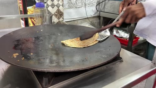 A man preparing lacha paratha at a shop in India