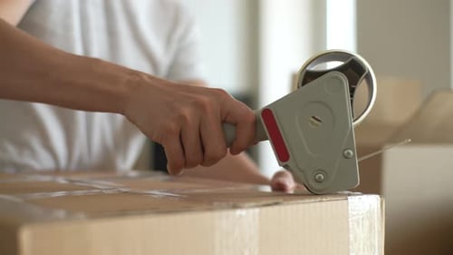Person Sealing Cardboard Box with Tape