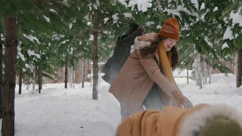 Cheerful Husband and Wife Having Snowball Fight with Son in Winter Park