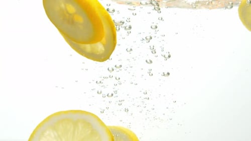Fresh lemon dropped into water with rising air bubbles, close up view