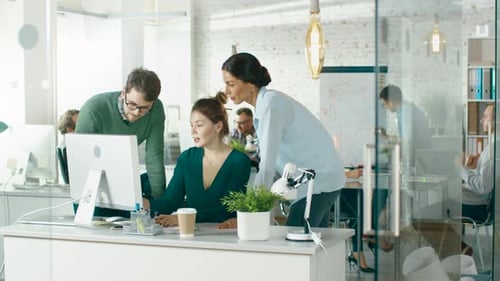 In Brightly Lit and Modern Creative Bureau. In Foreground Three People Discuss Business Issues Usin