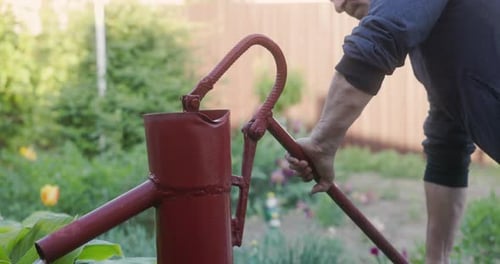 Caucasian Man Pumping Water With Manual Water Pump. closeup shot