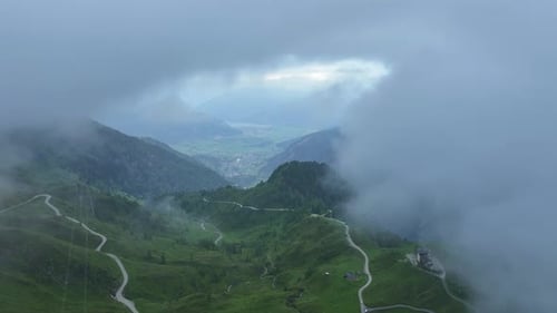 Partes de neblina revelam um belo prado verde estendido abaixo.
Aéreo
