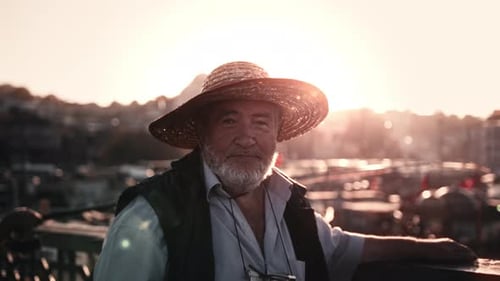 Man standing on bridge in Istanbul at sunset looking at camera