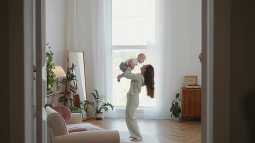 Mother Playing with Baby at Home in Sunlight