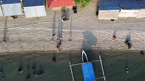 Aerial view of People bathing in the sun, swimming, and playing games on the beach