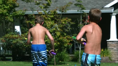 Boys have water gun fight in yard