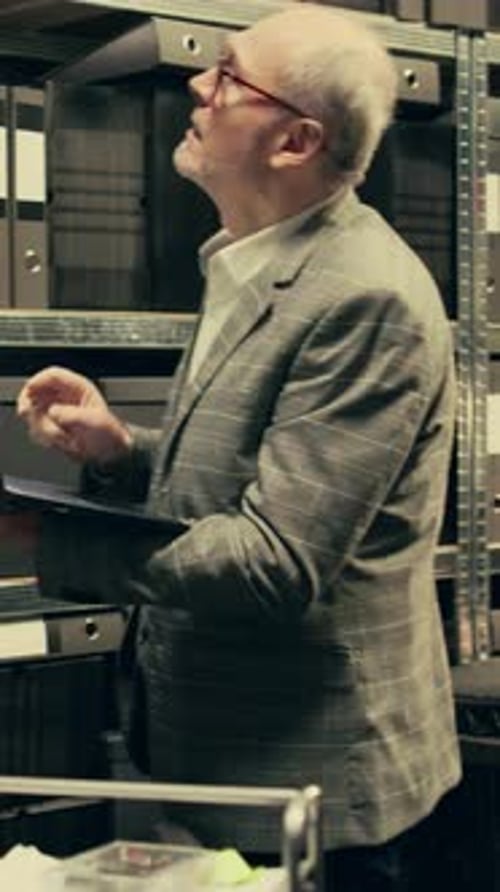 Man Uses Laptop in a Dark Records Room