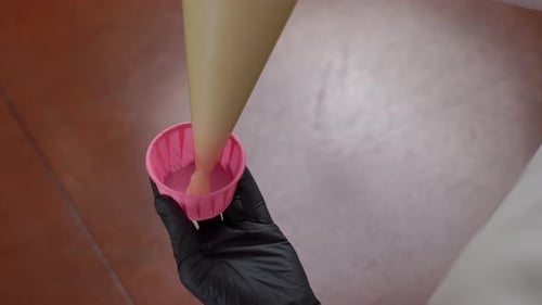 Top View Closeup Pouring Muffin Dough From Pastry Bag in Pink Form Indoors