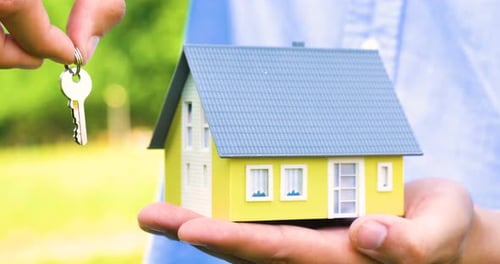 Hand Holding Miniature House with Key