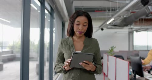 African american businesswoman using digital tablet while walking in office