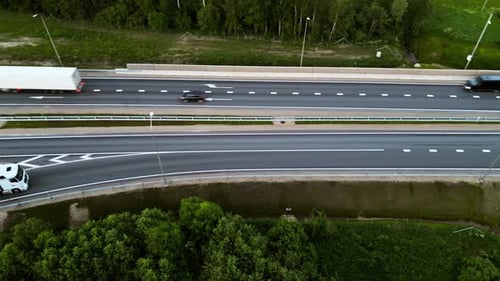 Luftaufnahme einer stark befahrenen Autobahn mit Lastwagen und Autos, umgeben von viel Grün, um einen Transport festzuhalten