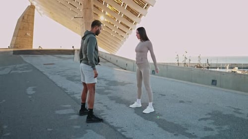 Personal Trainer Guiding Client Through Squats Near the Sea
