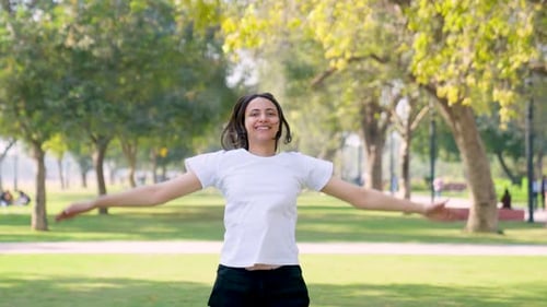 Enthusiastic Woman Doing Jumping Jacks in Park