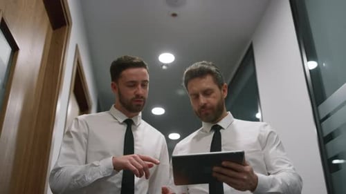 Two Managers Discuss Financial Business Data Using Digital Tablet in Office Centre