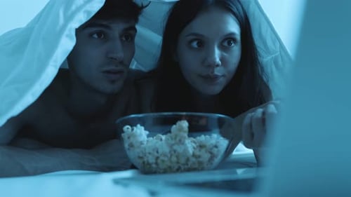Couple Watching a Scary Movie in Bed at Night