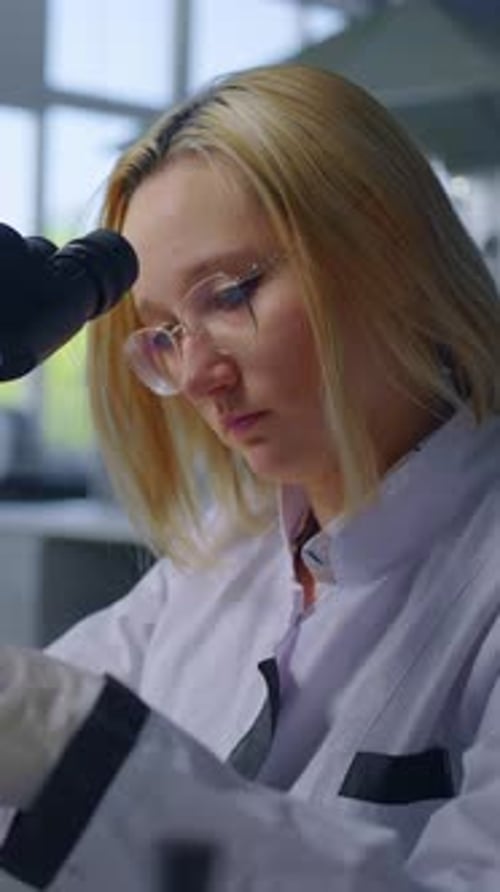 Young Woman Works with Microscope in Laboratory