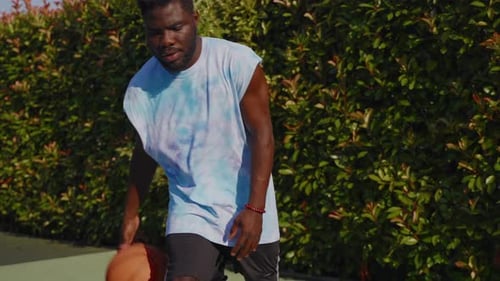 Young Adult Dribbling Basketball on Outdoor Court