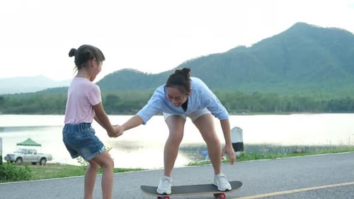 Mother and daughter learn to skateboard together in the park.