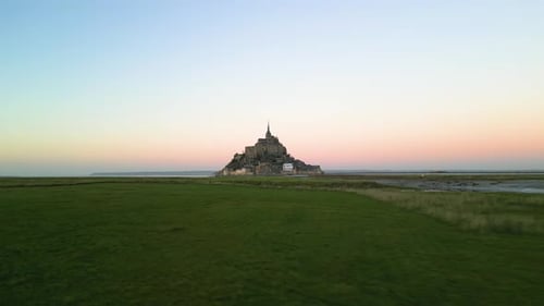 Aerial Drone View of Mont Saint-Michel Flying Over Grass from Left to Right at Sunset