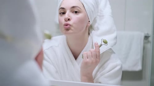 Woman Doing Face Massage in Bathroom Mirror