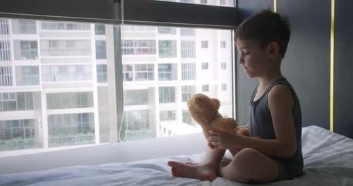 Young Boy Hugs Teddy Bear on Bed