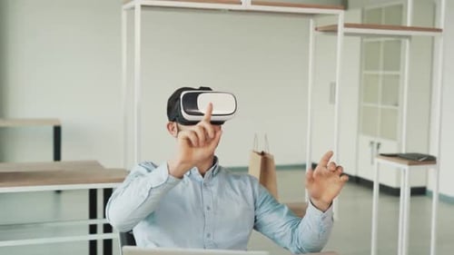 surprised man has a fascinating time sitting in a chair wearing virtual reality glasses