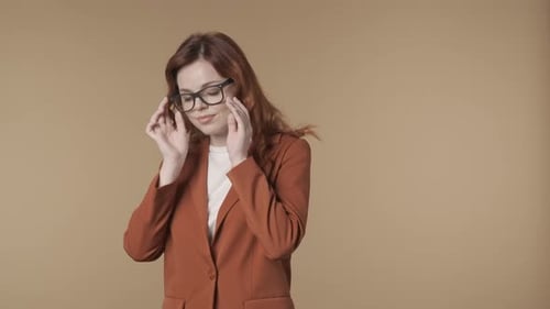 Vidéo isolée de taille moyenne d'une jeune femme satisfaite, timide et détendue en train de réparer les lunettes qu'elle porte