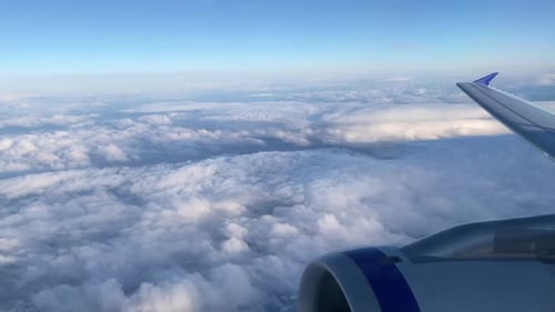 Vue depuis une fenêtre d'avion au-dessus des nuages avec un ciel bleu