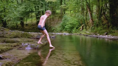 Boy Walks on Rocks in Water in Wild Forest Creative Boy in Swimming Trunks Walks on Water in Forest