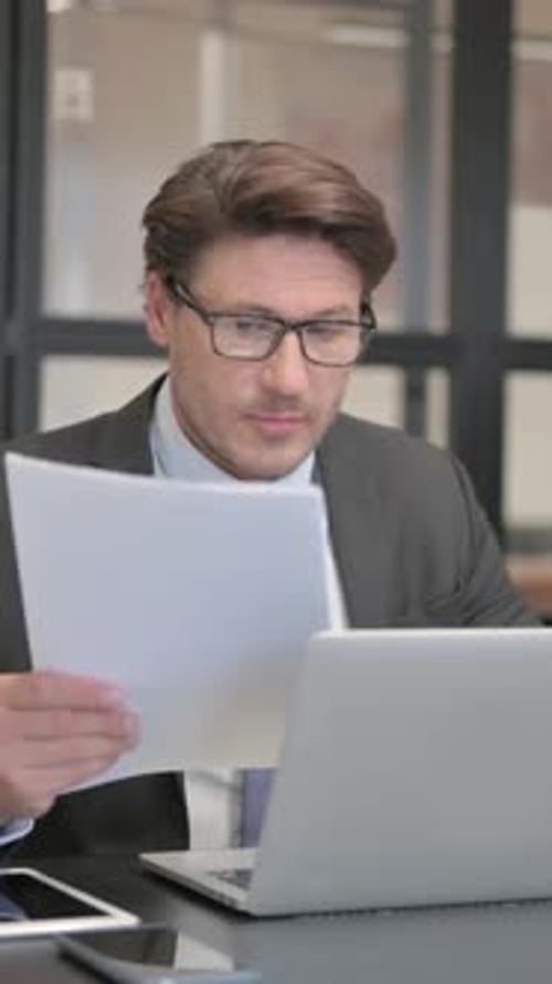 Man Working with Laptop and Documents in Office
