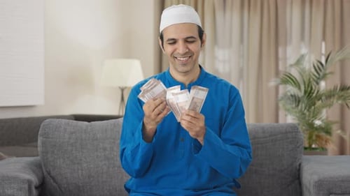 Man in Traditional Shirt Counts Currency at Home