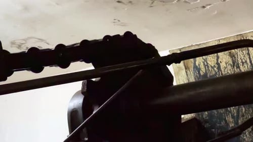 Cog wheel and industrial chain rotating in factory, close up view