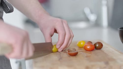 Person Slicing Colorful Cherry Tomatoes on Wooden Board