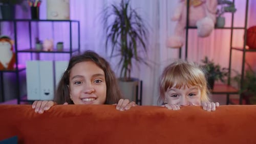 Irmãos sorridentes, crianças, meninas, brincando de esconde-esconde, tentando assustar uma pegadinha em casa
