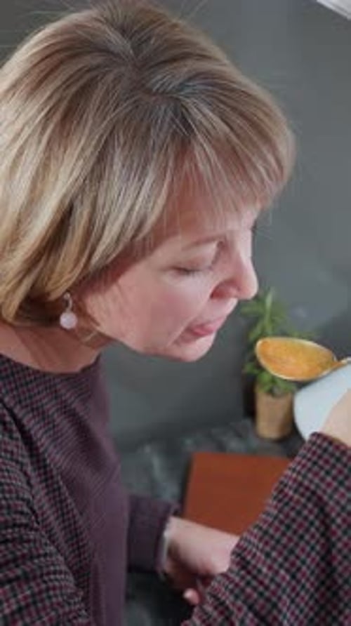 Overhead View of Woman Tasting Freshly Cooked Food in Bright Kitchen