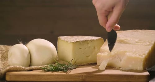 Cheese Assortment on Wooden Board Being Cut