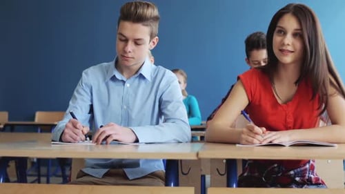 Education, People And Learning Concept - Group Of Students With Notebooks Writing Test At School