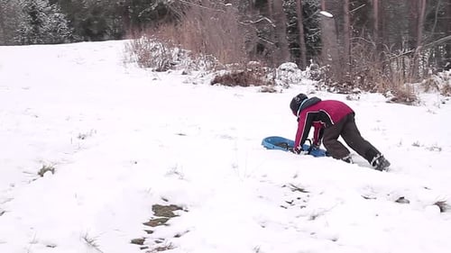 criança empurrando trenó na neve se divertindo descendo a colina — vídeo de stock