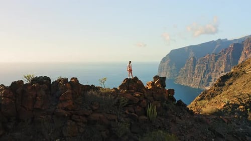 Woman Stands on Top of Mountain Enjoys Nature Landscape in Hike to Los Gigantes Cliffs with Ocean