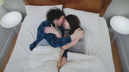 Happy Couple Cuddling and Laughing Together in Bed