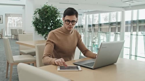 Young Adult Working on Laptop in Bright Office