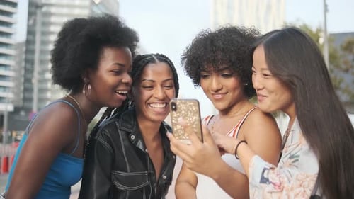 Four Young Women Friends Using Smartphone in City