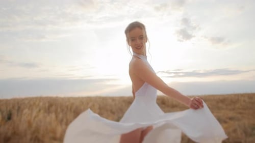Elegant Woman in White Dress Moving Amidst Field with Wheat